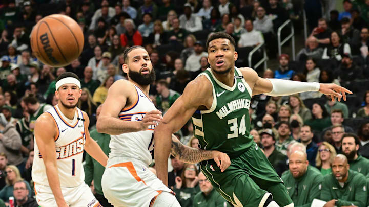 Apr 1, 2025; Milwaukee, Wisconsin, USA;  Milwaukee Bucks forward Giannis Antetokounmpo (34) looks for the ball against Phoenix Suns forward Cody Martin (17) and  guard Devin Booker (1) in the fourth quarter at Fiserv Forum. Mandatory Credit: Benny Sieu-Imagn Images