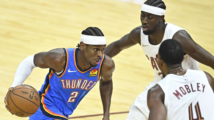 Oct 27, 2023; Cleveland, Ohio, USA; Oklahoma City Thunder guard Shai Gilgeous-Alexander (2) moves against Cleveland Cavaliers guard Caris LeVert (3) and forward Evan Mobley (4) in the first quarter at Rocket Mortgage FieldHouse. Mandatory Credit: David Richard-Imagn Images