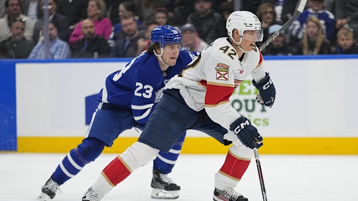 Apr 2, 2025; Toronto, Ontario, CAN; Florida Panthers defenseman Gustav Forsling (42) and Toronto Maple Leafs forward Matthew Knies (23) chase after a loose puck during the third period at Scotiabank Arena. Mandatory Credit: John E. Sokolowski-Imagn Images