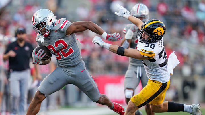 Oct 5, 2024; Columbus, OH, USA; Ohio State Buckeyes running back TreVeyon Henderson (32) fights off the tackle attempt by Iowa Hawkeyes defensive back Quinn Schulte (30) during the second half of the NCAA football game at Ohio Stadium. Ohio State won 35-7.