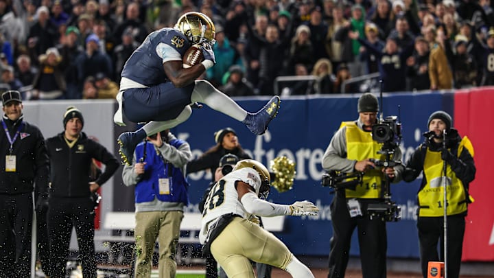 Notre Dame Fighting Irish running back Jeremiyah Love leaps over Army Black Knights cornerback Donavon Platt for a touchdown 