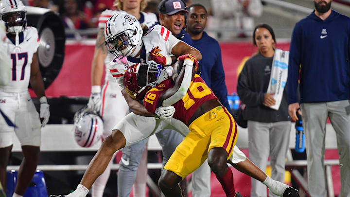 Oct 7, 2023; Los Angeles, California, USA; Southern California Trojans wide receiver Tahj Washington (16) is brought down by Arizona Wildcats safety Genesis Smith (12) during the second half at Los Angeles Memorial Coliseum. Mandatory Credit: Gary A. Vasquez-Imagn Images