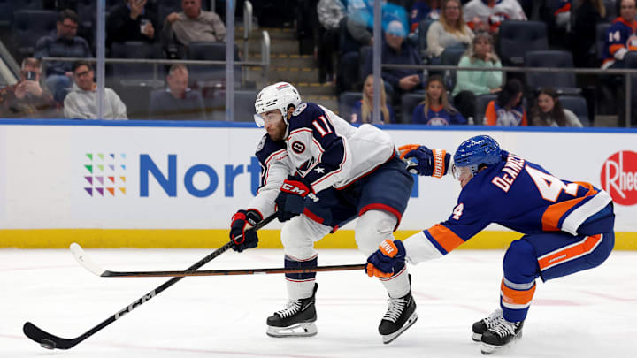 Mar 24, 2025; Elmont, New York, USA; Columbus Blue Jackets center Luke Kunin (11) takes a shot against New York Islanders defenseman Tony DeAngelo (4) during the first period at UBS Arena. Mandatory Credit: Brad Penner-Imagn Images