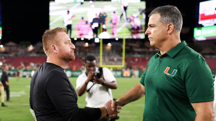 Sep 21, 2024; Tampa, Florida, USA;  Miami Hurricanes head coach Mario Cristobal greet South Florida Bulls head coach Alex Goulash after a game at Raymond James Stadium. Mandatory Credit: Nathan Ray Seebeck-Imagn Images