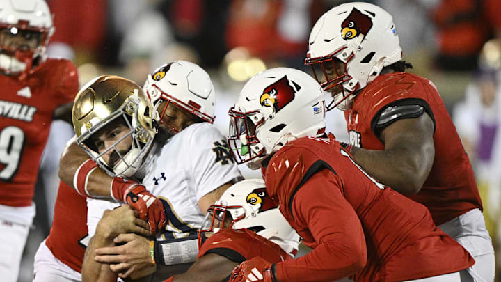 Oct 7, 2023; Louisville, Kentucky, USA; Notre Dame Fighting Irish quarterback Sam Hartman (10) is wrapped up by four Louisville Cardinals defenders during the second half at L&N Federal Credit Union Stadium. Louisville defeated Notre Dame 33-20. Oct 7, 2023; Louisville, Kentucky, USA; Notre Dame Fighting Irish quarterback Sam Hartman (10) is wrapped up by four Louisville Cardinals defenders during the second half at L&N Federal Credit Union Stadium. Louisville defeated Notre Dame 33-20.