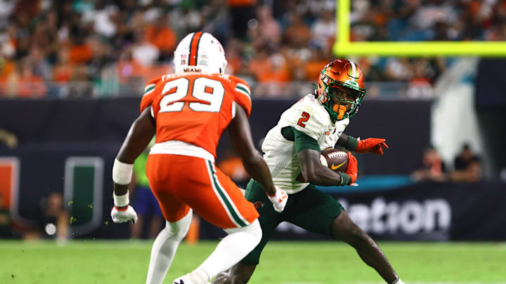 Sep 7, 2024; Miami Gardens, Florida, USA; Florida A&M Rattlers wide receiver Jamari Gassett (2) runs with the football against Miami Hurricanes defensive back OJ Frederique Jr. (29) during the third quarter at Hard Rock Stadium. Mandatory Credit: Sam Navarro-Imagn Images