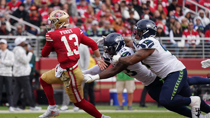 Nov 17, 2024; Santa Clara, California, USA; San Francisco 49ers quarterback Brock Purdy (13) scrambles away from Seattle Seahawks linebacker Boye Mafe (53) and Seattle Seahawks defensive tackle Byron Murphy II (91) in the third quarter at Levi's Stadium. Mandatory Credit: David Gonzales-Imagn Images
