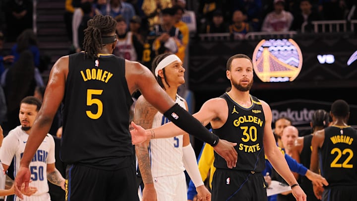 Golden State Warriors guard Stephen Curry (30) high fives forward Kevon Looney (5) as a timeout is called during the fourth quarter against the Orlando Magic at Chase Center. Mandatory Credit: Kelley L Cox-Imagn Images