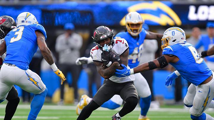 Dec 15, 2024; Inglewood, California, USA; Tampa Bay Buccaneers running back Bucky Irving (7) runs the ball against Los Angeles Chargers linebacker Daiyan Henley (0) and safety Derwin James Jr. (3) during the first half at SoFi Stadium. Mandatory Credit: Gary A. Vasquez-Imagn Images Dec 15, 2024; Inglewood, California, USA; Tampa Bay Buccaneers running back Bucky Irving (7) runs the ball against Los Angeles Chargers linebacker Daiyan Henley (0) and safety Derwin James Jr. (3) during the first half at SoFi Stadium. Mandatory Credit: Gary A. Vasquez-Imagn Images