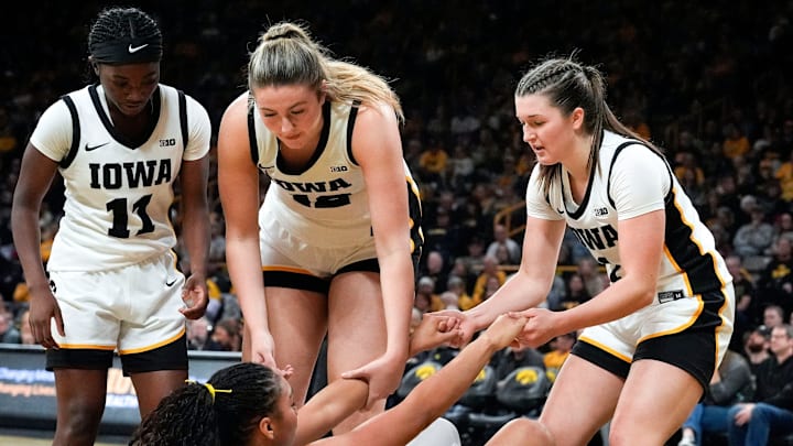 Iowa guard Chit-Chat Wright (11), Iowa center Layla Hays (12), and Iowa guard Taylor Stremlow (1) help up Iowa forward Hannah Stuelke (45) Dec. 28, 2025 at Carver-Hawkeye Arena in Iowa City, Iowa.