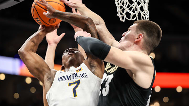 Mar 12, 2025; Kansas City, MO, USA; West Virginia Mountaineers guard Javon Small (7) and Colorado Buffaloes forward Andrej Jakimovski (23) collide under the basket during the first half at T-Mobile Center. 