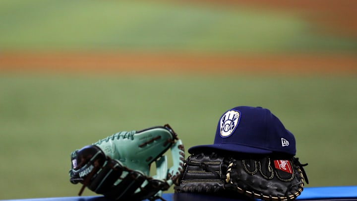 May 7, 2021; Miami, Florida, USA; Baseball gloves and a Milwaukee Brewers hat rest over a handrail in the Brewers    dugout prior a game against the Miami Marlins at loanDepot park. Mandatory Credit: Sam Navarro-Imagn Images