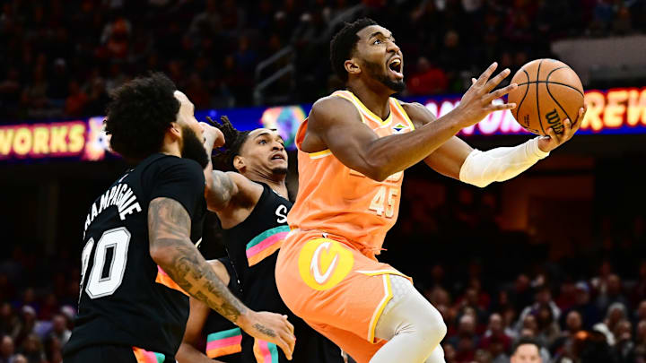 Dec 5, 2025; Cleveland, Ohio, USA; Cleveland Cavaliers guard Donovan Mitchell (45) drives to the basket against San Antonio Spurs guard Devin Vassell (24) and forward Julian Champagnie (30) during the second half at Rocket Arena. Mandatory Credit: Ken Blaze-Imagn Images