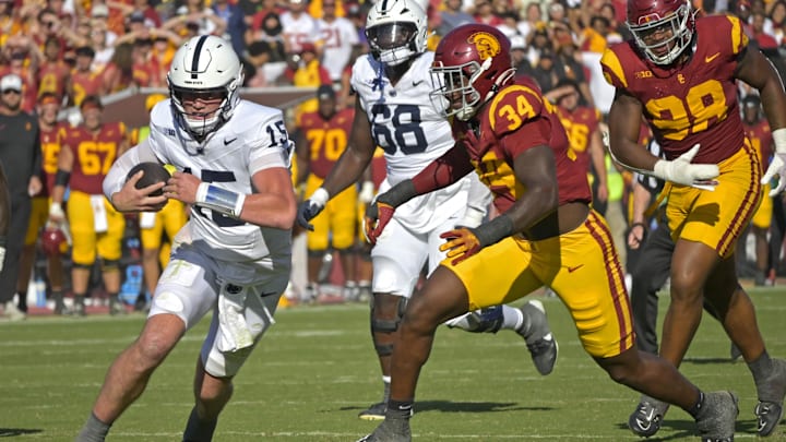Penn State Nittany Lions quarterback Drew Allar (15) avoids USC Trojans defensive end Braylan Shelby (34) as he carries the ball for a short a short gain. 