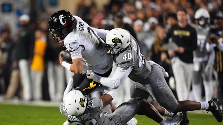 Oct 26, 2024; Boulder, Colorado, USA; Colorado Buffaloes defensive end Taje McCoy (40) and safety Carter Stoutmire (23) tackle Cincinnati Bearcats quarterback Brendan Sorsby (2) in the fourth quarter at Folsom Field. Mandatory Credit: Ron Chenoy-Imagn Images Oct 26, 2024; Boulder, Colorado, USA; Colorado Buffaloes defensive end Taje McCoy (40) and safety Carter Stoutmire (23) tackle Cincinnati Bearcats quarterback Brendan Sorsby (2) in the fourth quarter at Folsom Field. Mandatory Credit: Ron Chenoy-Imagn Images