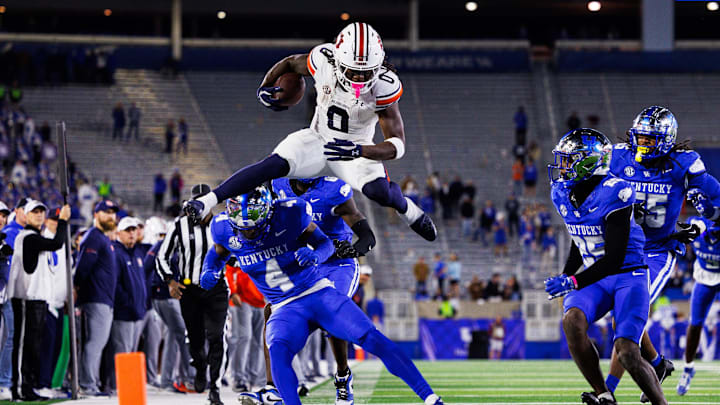 Oct 26, 2024; Lexington, Kentucky, USA; Auburn Tigers running back Damari Alston (0) hurdles Kentucky Wildcats defensive back Kristian Story (4) during the fourth quarter at Kroger Field. Mandatory Credit: Jordan Prather-Imagn Images