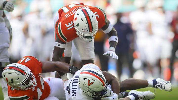 Oct 28, 2023; Miami Gardens, Florida, USA; Virginia Cavaliers running back Mike Hollins (7) runs with the football against Miami Hurricanes defensive lineman Rueben Bain Jr. (44) and linebacker Wesley Bissainthe (31) during the first quarter at Hard Rock Stadium. Mandatory Credit: Sam Navarro-USA TODAY Sports