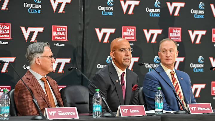 Nov 19, 2025; Blacksburg, VA, USA;  Virginia Tech head coach James Franklin (center) speaks as Virginia Tech President Timothy Sands (left) and Athletic Director Whit Babcock (right) looks on at Cassell Coliseum. Mandatory Credit: Brian Bishop-Imagn Images