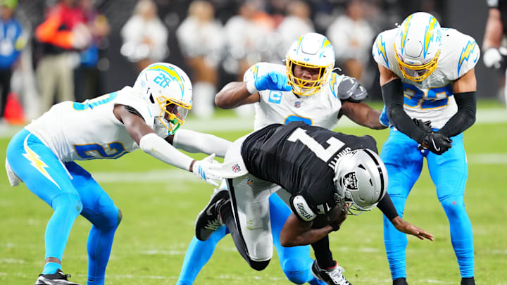 Sep 15, 2025; Paradise, Nevada, USA; Las Vegas Raiders quarterback Geno Smith (7) is tackled by Los Angeles Chargers cornerback Cam Hart (20), Los Angeles Chargers linebacker Daiyan Henley (0) and Los Angeles Chargers safety Alohi Gilman (32) during the second quarter at Allegiant Stadium. Mandatory Credit: Stephen R. Sylvanie-Imagn Images