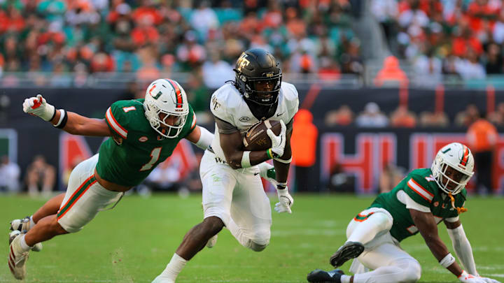 Nov 23, 2024; Miami Gardens, Florida, USA; Wake Forest Demon Deacons running back Demond Claiborne (1) runs with the football past Miami Hurricanes linebacker Francisco Mauigoa (1) during the second quarter at Hard Rock Stadium. Mandatory Credit: Sam Navarro-Imagn Images
