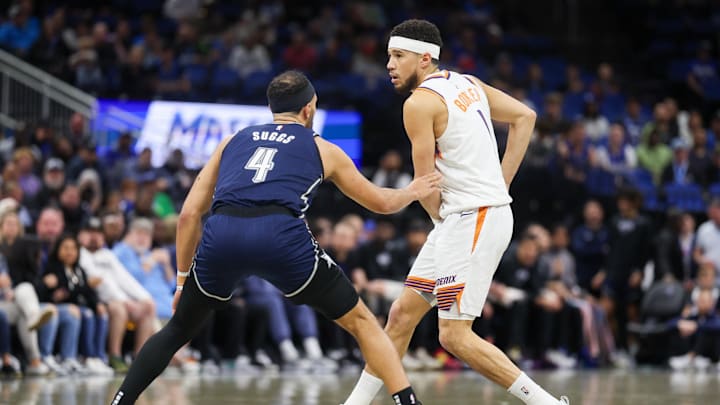 Jan 28, 2024; Orlando, Florida, USA;  Phoenix Suns guard Devin Booker (1) looks to pass the ball guarded by Orlando Magic guard Jalen Suggs (4) in the first quarter at the Kia Center. Mandatory Credit: Nathan Ray Seebeck-Imagn Images
