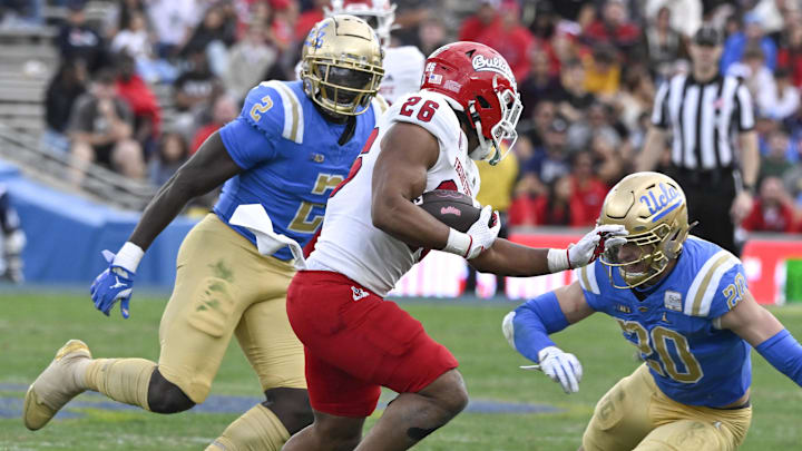 Nov 30, 2024; Pasadena, California, USA; Fresno State Bulldogs running back Bryson Donelson (26) tries to run past UCLA Bruins linebacker Kain Medrano (20) and linebacker Oluwafemi Oladejo (2) during the third quarter at Rose Bowl. Mandatory Credit: Robert Hanashiro-Imagn Images