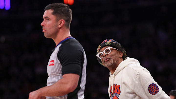 Apr 6, 2025; New York, New York, USA; American actor and director Spike Lee tends behind referee Andy Nagy (83) during the second half of the game against the Phoenix Suns at Madison Square Garden. Mandatory Credit: Vincent Carchietta-Imagn Images
