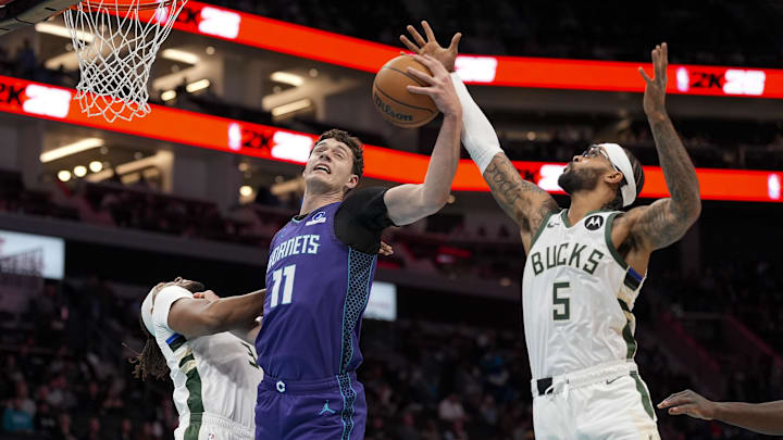 Nov 12, 2025; Charlotte, North Carolina, USA; Charlotte Hornets center Ryan Kalkbrenner (11) grabs the rebound from Milwaukee Bucks guard Gary Trent Jr. (5) during the first quarter at Spectrum Center. Mandatory Credit: Jim Dedmon-Imagn Images