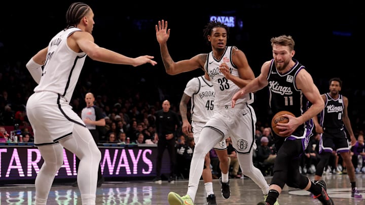 Jan 27, 2025; Brooklyn, New York, USA; Sacramento Kings forward Domantas Sabonis (11) drives to the basket against Brooklyn Nets center Nic Claxton (33) and forward Jalen Wilson (22) during the third quarter at Barclays Center. Mandatory Credit: Brad Penner-Imagn Images
