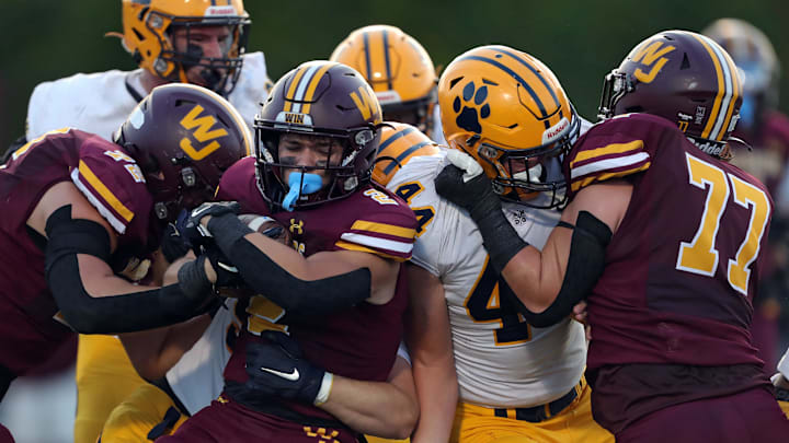 Walsh Jesuit running back Lucas Weaver, center, pushes forward for yards with help from linemen Colton Crosley, left, and Kodey Kish, right, during the first half, Friday, Sept. 13, 2024.