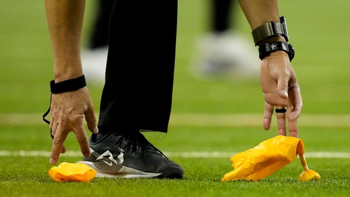 An official picks up two flags from the field Sunday, Nov. 30, 2025, during a game between the Indianapolis Colts and the Houston Texans at Lucas Oil Stadium in Indianapolis.