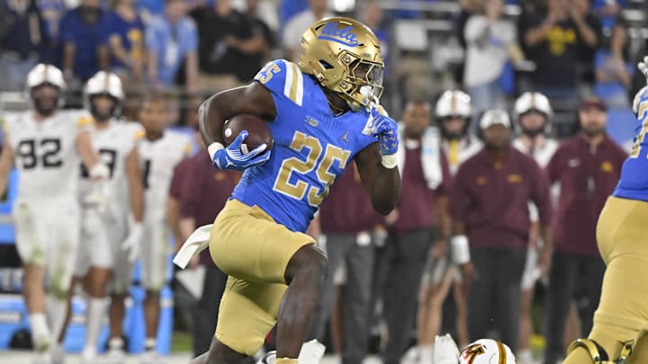 Oct 12, 2024; Pasadena, California, USA; UCLA Bruins running back T.J. Harden (25) high steps past Minnesota Golden Gophers linebacker Devon Williams (9) during the fourth quarter  at Rose Bowl. Mandatory Credit: Robert Hanashiro-Imagn Images