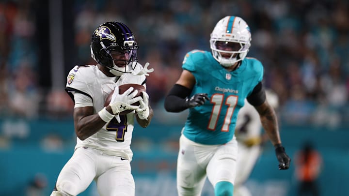 Baltimore Ravens wide receiver Zay Flowers (4) catches the ball under pressure from Miami Dolphins safety Dante Trader Jr. (11) during the third quarter at Hard Rock Stadium. 