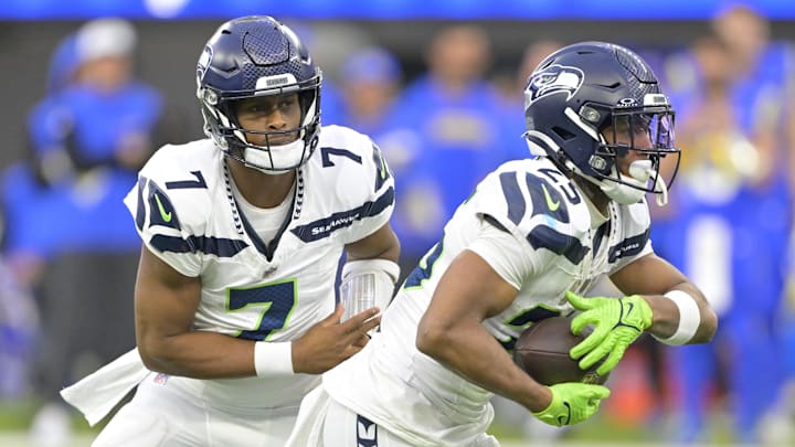 Jan 5, 2025; Inglewood, California, USA; Seattle Seahawks quarterback Geno Smith (7) hands off to running back Kenny McIntosh (25) against the Los Angeles Rams at SoFi Stadium. Mandatory Credit: Jayne Kamin-Oncea-Imagn Images