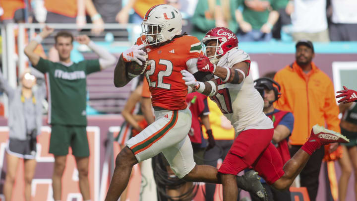 Nov 18, 2023; Miami Gardens, Florida, USA; Miami Hurricanes running back Mark Fletcher Jr. (22) runs with the football against Louisville Cardinals defensive back Devin Neal (27) during the third quarter at Hard Rock Stadium. Mandatory Credit: Sam Navarro-USA TODAY Sports Nov 18, 2023; Miami Gardens, Florida, USA; Miami Hurricanes running back Mark Fletcher Jr. (22) runs with the football against Louisville Cardinals defensive back Devin Neal (27) during the third quarter at Hard Rock Stadium. Mandatory Credit: Sam Navarro-USA TODAY Sports