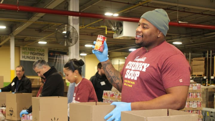November 19, 2024; Hillside, New Jersey, USA; New York Giants defensive tackle Dexter Lawrence II helps package Campbell's soup. 