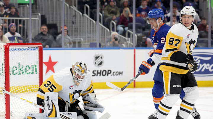 Dec 28, 2024; Elmont, New York, USA; Pittsburgh Penguins goaltender Tristan Jarry (35) makes a save in front of New York Islanders left wing Anders Lee (27) and Penguins center Sidney Crosby (87) during the second period at UBS Arena. Mandatory Credit: Brad Penner-Imagn Images