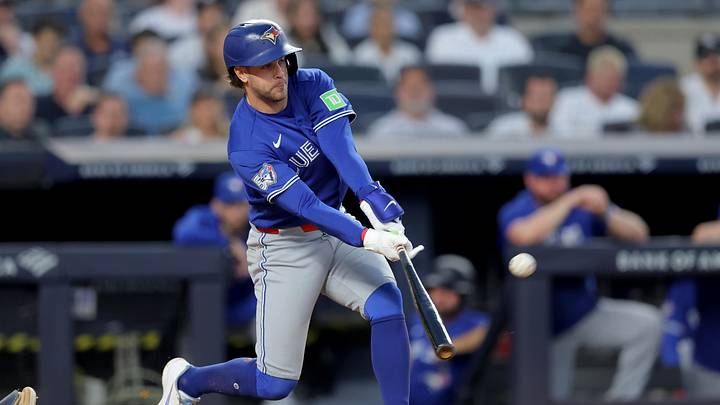 Ernie Clement hits a baseball for a home run in a blue Blue Jays jerse
