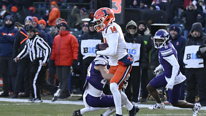 Nov 30, 2024; Chicago, Illinois, USA; Illinois Fighting Illini defensive back Xavier Scott (14) is stopped by Northwestern Wildcats wide receiver Drew Wagner (48) after he makes a n interception against Northwestern Wildcats during the first half at Wrigley Field. Mandatory Credit: Matt Marton-Imagn Images Nov 30, 2024; Chicago, Illinois, USA; Illinois Fighting Illini defensive back Xavier Scott (14) is stopped by Northwestern Wildcats wide receiver Drew Wagner (48) after he makes a n interception against Northwestern Wildcats during the first half at Wrigley Field. Mandatory Credit: Matt Marton-Imagn Images
