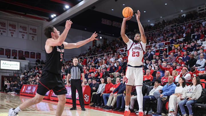 Dec 23, 2025; Queens, New York, USA;  St. John's basketball forward Bryce Hopkins (23) takes a three point shot past Harvard Crimson guard Ben Eisendrath (5) in the second half at Carnesecca Arena.
