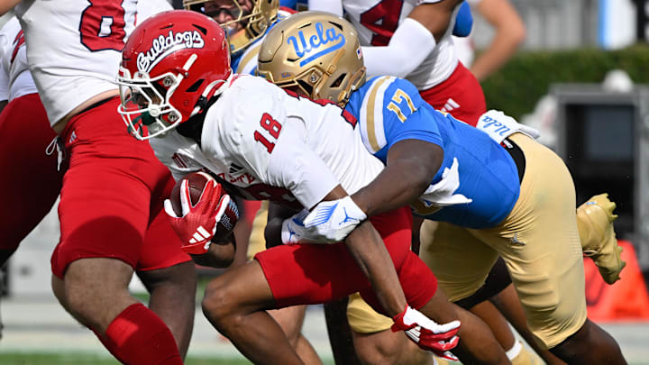 Nov 30, 2024; Pasadena, California, USA; Fresno State Bulldogs wide receiver Jalen Moss (18) tries to break away from UCLA Bruins linebacker Jalen Woods (17) during the second quarter at Rose Bowl. Mandatory Credit: Robert Hanashiro-Imagn Images