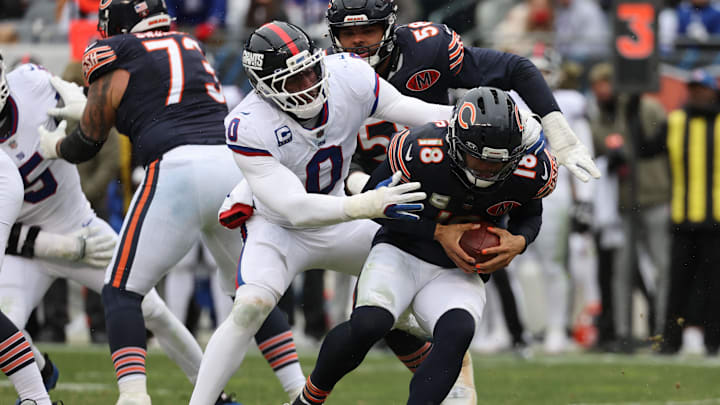 Nov 9, 2025; Chicago, Illinois, USA; Chicago Bears quarterback Caleb Williams (18) avoids the sack by New York Giants linebacker Brian Burns (0) during the second half at Soldier Field.  