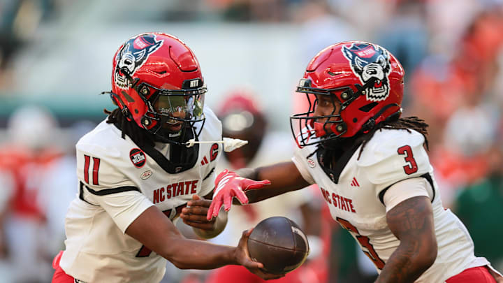 Nov 15, 2025; Miami Gardens, Florida, USA; NC State Wolfpack quarterback CJ Bailey (11) hands off the football to running back Hollywood Smothers (3) during the first quarter at Hard Rock Stadium. Mandatory Credit: Sam Navarro-Imagn Images