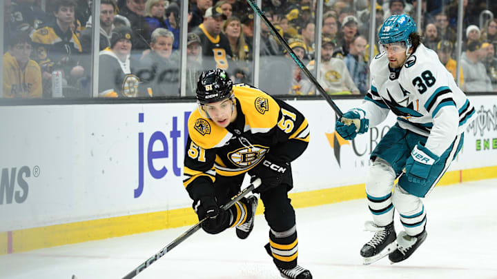 Jan 20, 2025; Boston, Massachusetts, USA;  Boston Bruins center Matthew Poitras (51) controls the puck ahead of San Jose Sharks defenseman Mario Ferraro (38) during the third period at TD Garden. Mandatory Credit: Bob DeChiara-Imagn Images