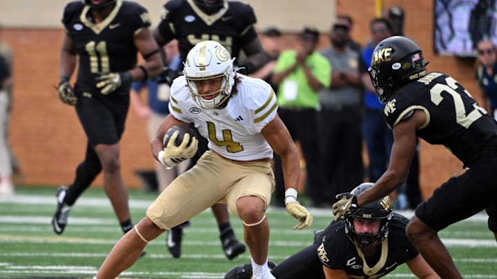 Sep 27, 2025; Winston-Salem, North Carolina, USA;  Georgia Tech Yellow Jackets wide receiver Isiah Canion (4) runs the ball against Wake Forest Demon Deacons defensive back Nick Andersen (45) and defensive back Braylon Johnson (23) during the fourth quarter at Allegacy Federal Credit Union Stadium. Mandatory Credit: Zachary Taft-Imagn Images