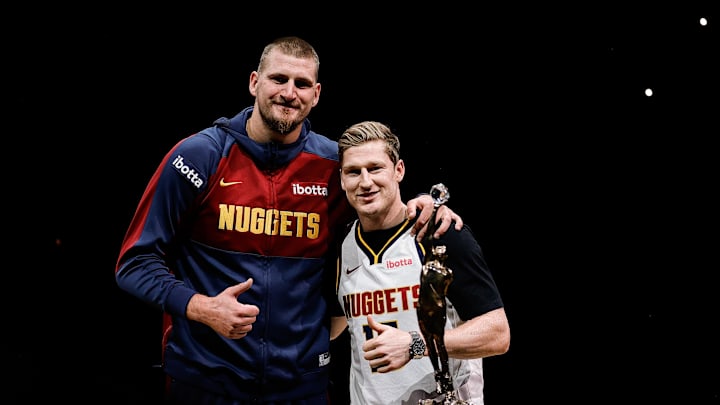 Oct 26, 2024; Denver, Colorado, USA; Colorado Avalanche player Nathan MacKinnon (R) presents Denver Nuggets center Nikola Jokic (L) with his KIA NBA MVP trophy before the game against the Los Angeles Clippers at Ball Arena. Mandatory Credit: Isaiah J. Downing-Imagn Images