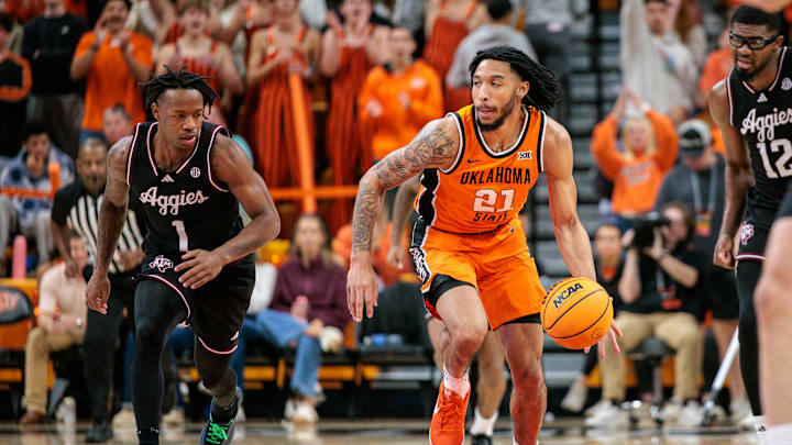 Nov 9, 2025; Stillwater, Oklahoma, USA; Oklahoma State Cowboys guard Isaiah Coleman (21) brings the ball up court around Texas A&M Aggies guard Josh Holloway (1) during the first half at Gallagher-Iba Arena. Mandatory Credit: William Purnell-Imagn Images