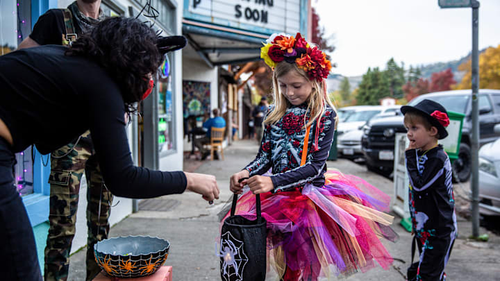 Two kids dressed in Halloween costumes are seen getting candy