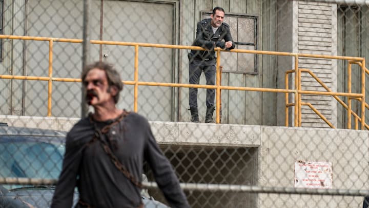 Simon as a walker is chained to the Sanctuary fence as Negan watches on