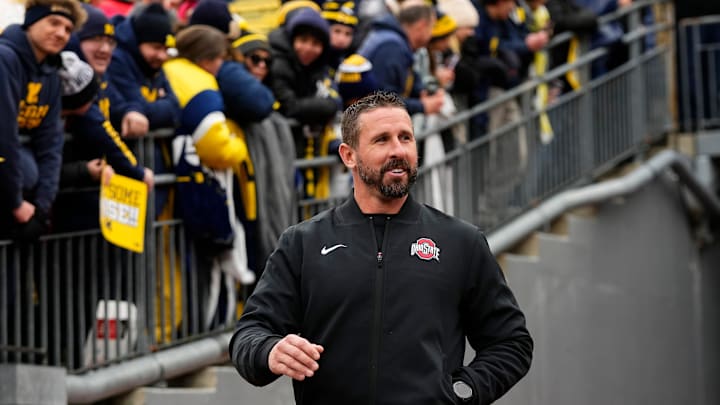 Ohio State Buckeyes offensive coordinator Brian Hartline laughs after hearing jeers as he walks onto the field prior to the NCAA football game against the Michigan Wolverines at Michigan Stadium in Ann Arbor, Mich. on Nov. 29, 2025. Ohio State Buckeyes offensive coordinator Brian Hartline laughs after hearing jeers as he walks onto the field prior to the NCAA football game against the Michigan Wolverines at Michigan Stadium in Ann Arbor, Mich. on Nov. 29, 2025.